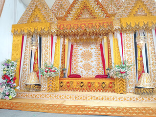 Indonesia Traditional wedding decorations with gold embroidery, vibrant fabrics, and floral accents, showcasing Indonesian cultural heritage.