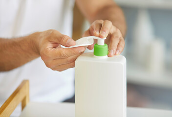 Personal hygiene and self-care concept. Close-up of male hands holds cotton pad and dispensing liquid cosmetic product from pump bottle, doing daily grooming and skincare routine in the morning © Studio Romantic