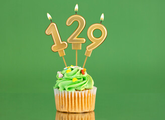 Birthday card with candle and cupcake - Number 129 on a green background