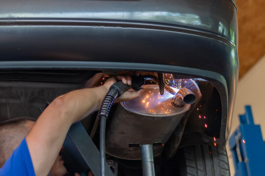 Car pipe exhaust welding. Masters replacing of  rear muffler of exhaust system in car workshop. Car exhaust system repair.