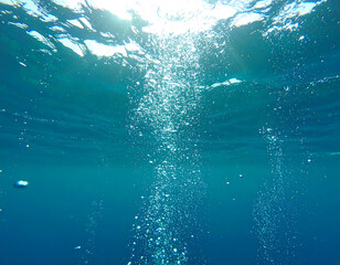 Underwater Air Bubbles Rising in Teal Ocean Water; Sunlit, Serene, and Tranquil Scene.