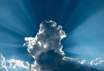 Dramatic sky with deep blue sky, backlit clouds and sunbeams.