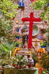 Decorated May Crosses altar in Granada featuring a large red floral cross, Virgin Mary figure,...