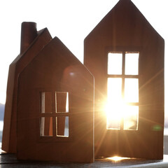 3 wooden European-style pretend house blocks with windows arranged with sunset flaring through....