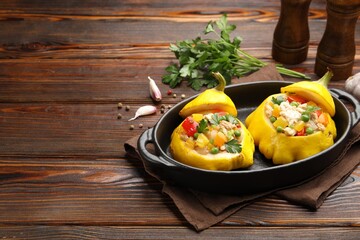Tasty stuffed pattypan squashes in baking dish on wooden table. Space for text