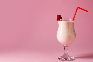 Tasty raspberry milkshake in glass on pink background, space for text