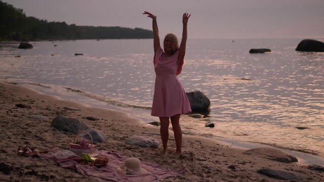 woman in pink dress dancing on sandy beach at suns
