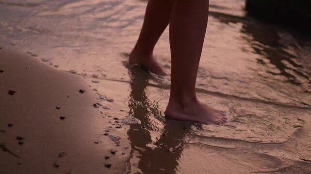 woman legs walking on sandy beach at sunset