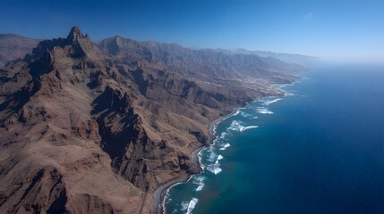High-angle view of a dramatic coastline, showcasing rugged mountains meeting the deep blue ocean.