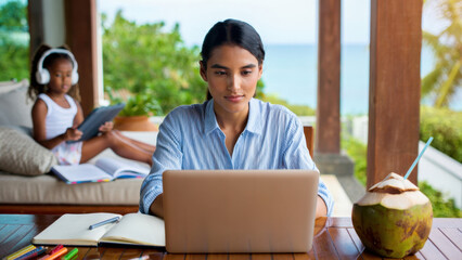 Remote working mom, digital nomad family, tropical workspace, homeschooling by the beach, online learning with kids, laptop lifestyle, family workcation, remote education, work abroad with child