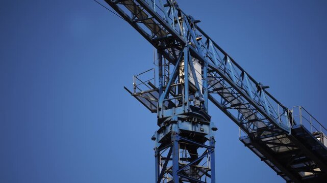 Crane and building under construction against blue sky