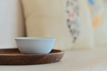 Elegant white porcelain teacup placed on wooden tray captured in close-up under gentle indoor...