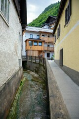 Fototapeta premium Scenic narrow street with stream through old buildings, Hallstatt, Austria