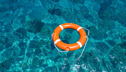 Bright Orange Lifebuoy Floating on Clear Turquoise Water Under Sunlight