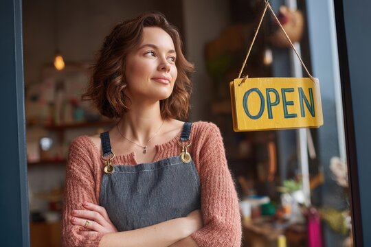 Woman standing near open sign in shop window