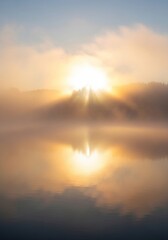 Fototapeta premium Ethereal Sunburst Through Morning Mist with Golden Lake Reflection