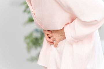 お腹を抱えるシニア女性