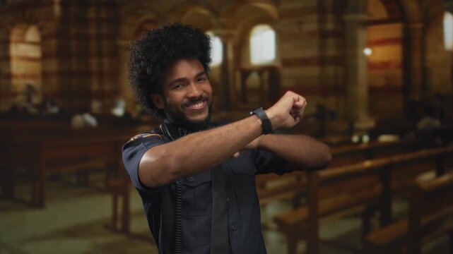 African american man in police uniform joyfully dances inside a church, capturing a moment of happiness and breaking stereotypes in a spiritual setting.