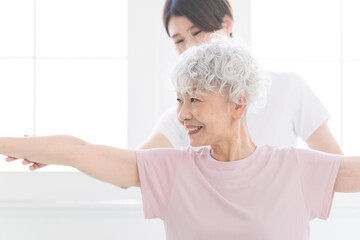 インストラクターにヨガポーズを教わるシニア女性　健康イメージ