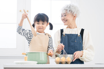 キッチンに立つ女の子とシニア女性　料理イメージ