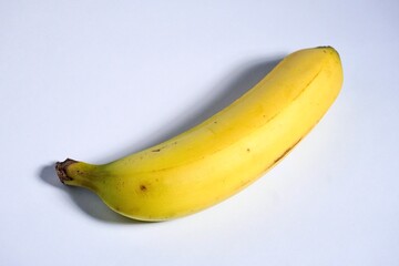 One yellow and slightly green banana fruit isolated on horizontal white background.