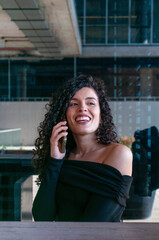 Confident young woman smiling while talking on smartphone outdoors