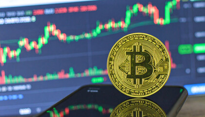 Bitcoin's Market View: A shiny gold bitcoin coin rests on a smartphone, showcasing the dynamic world of cryptocurrency trading, with the market's fluctuating indicators in the backdrop.