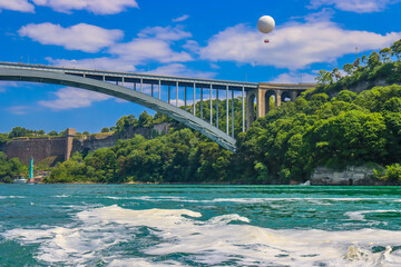 The gushing turquoise water from the Niagara falls with blue sky and white clouds the beautify scenry of nature
