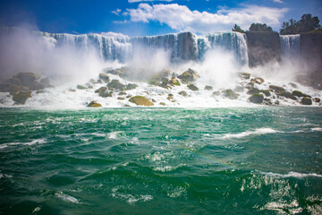 The gushing turquoise water from the Niagara falls with blue sky and white clouds the beautify scenry of nature