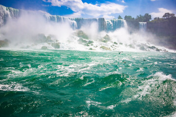 The gushing turquoise water from the Niagara falls with blue sky and white clouds the beautify scenry of nature