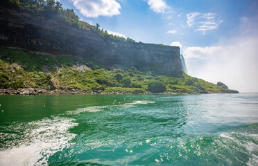 The gushing turquoise water from the Niagara falls with blue sky and white clouds the beautify scenry of nature