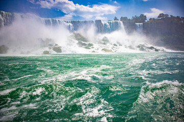 The gushing turquoise water from the Niagara falls with blue sky and white clouds the beautify scenry of nature