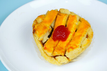 A delicious lattice-topped pie or tart with a cherry on top, served on a white plate with a light blue background.