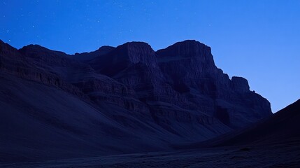Fototapeta premium Dramatic mountain range silhouette against twilight sky with visible stars provides a sense of awe