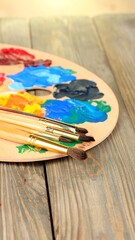 Fototapeta premium Artist's palette and brushes on a wooden surface