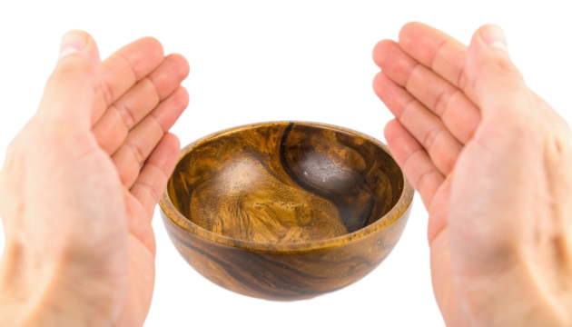 Empty wooden bowl held aloft by outstretched hands, showcasing the natural wood grain and warm tones.