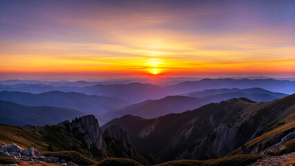 Obraz premium Beautiful sunset over layered mountains in soft glowing orange , yellow and purple , calm atmosphere, radiant with natural beauty