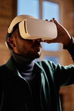 African young bearded man watching video using virtual reality simulator at office