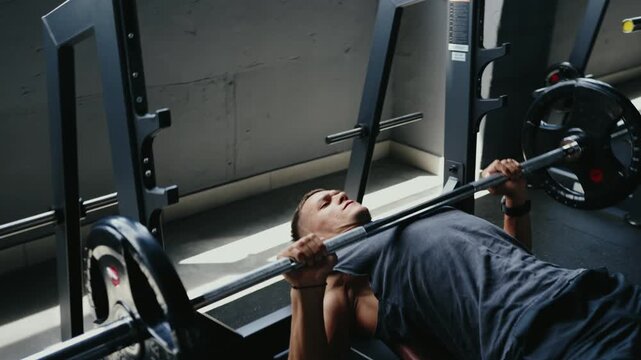A man engaging in a bench press workout at the gym. He is lifting heavy weights for strength training, promoting fitness and muscle growth. Dedication and effort shown in his expression.