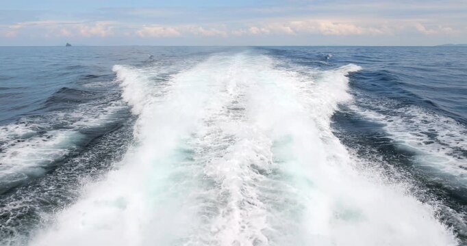 Powerful white wake on calm sea water, viewed from stern of modern catamaran ferry sailing towards Tioman Island. Wide wake of foam and small splashes, turquoise color seen in middle