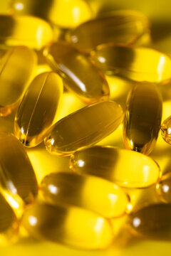 Closeup photo of yellow Omega-3 Fish Oil on yellow background 