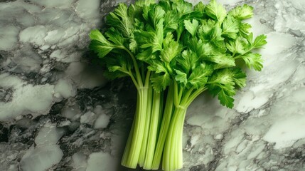 Fresh celery stalks with vibrant green leaves on a gray marble surface