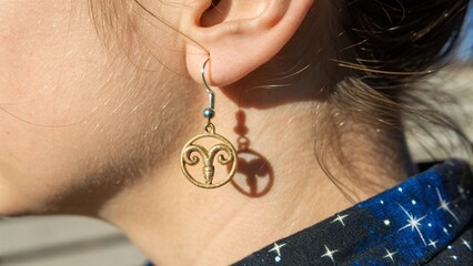 Close Up of Human Ear with Golden Aries Zodiac Symbol Earring for Astrology Concept
