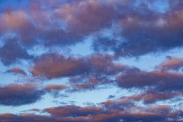 Dramatic sky filled with layered clouds tinted with warm evening light against a blue backdrop