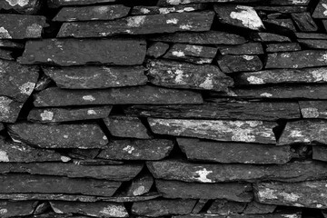 Black and white detail of a traditional dry stone wall built with irregular slate rocks