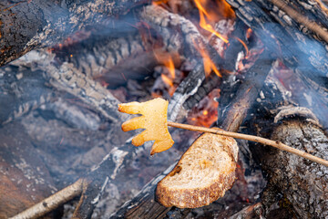 a slice of toasted bread with fried bacon an open fire in nature, slanina,traditional food in...