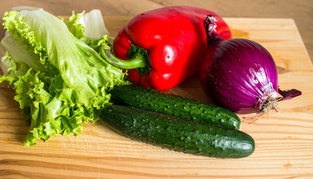 Fresh Harvest of Vegetables: Vibrant, fresh vegetables rest artfully on a rustic cutting board, an inviting image of culinary inspiration. Red bell pepper, purple onion, crisp cucumber.