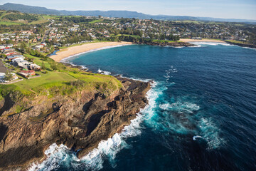 The beautifully scenic coastal town of Kiama, located just south of Sydney featuring iconic Kendalls & Surf Beaches. Captured from high above a dark blue ocean on sunrise.