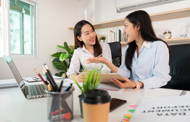 Engaging Discussion. Two women collaborating on business strategies in a bright office.