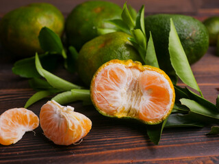 Jeruk keprok, fresh tangerines with green leaves on wooden table, fresh orange fruit, ripe...